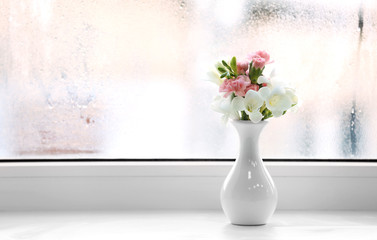 Beautiful spring flowers in vase on windowsill background