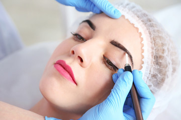 Cosmetologist applying permanent make up on eyebrows