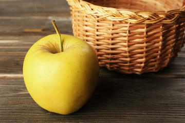 Apple with wicker basket on wooden background