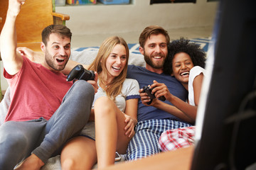 Group Of Friends Wearing Pajamas Playing Video Game Together