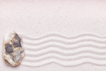Zen garden with a dark marble rock and wave pattern in the sand