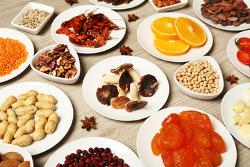 Different products on saucers on wooden table, top view