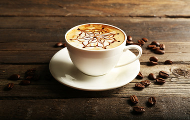 Cup of latte art coffee with grains on wooden background