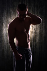 Silhouette photo of young sporty man demonstrating muscles