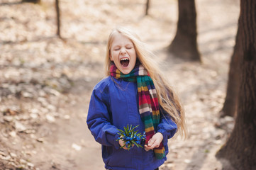 Beautiful little blond girl in a bright scarf yawns 