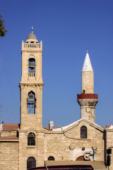 Fototapeta premium Orthodox church bell tower next to the mosque minaret, Cyprus