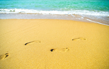 Fototapeta na wymiar Footprints on the beach sand by the sea