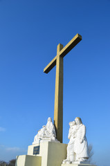 Large cross and white statues in dunes