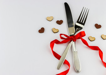 Top view of silver fork and knife decorated red ribbon with bow 