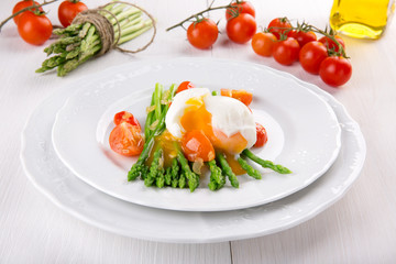 Green asparagus stems with soft-boiled egg, tomato and sauce.