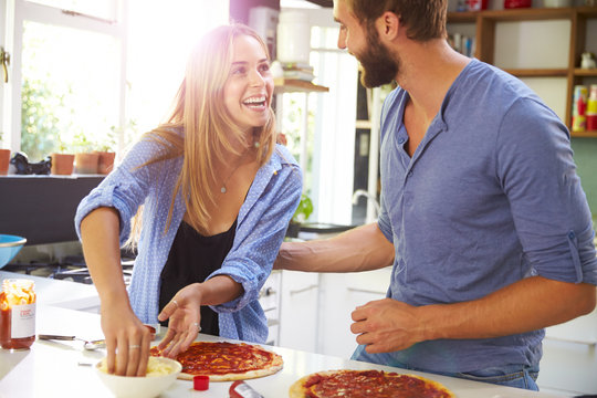 Young Couple Making Pizza In Kitchen Together