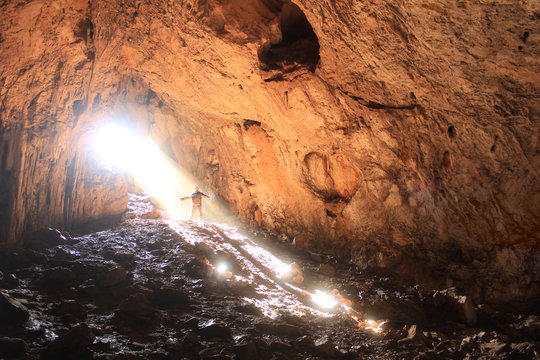 big cave with small human and sun rays in it
