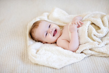 Baby wrapped in a towel lying on a bed