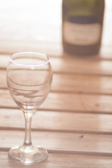Wine glass with bottle on wooden background dreamy look