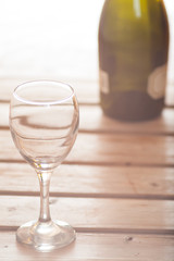 Wine glass with bottle on wooden background dreamy look
