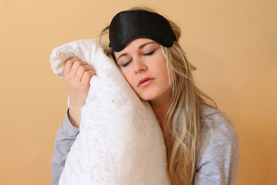 Sleepy young women with pillow and sleeping eye mask still on.