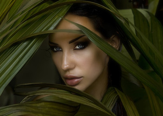 Sexy beautiful woman hiding behind the palm leaves. Beautiful st