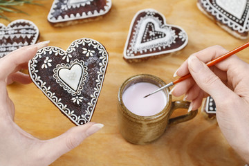 Woman decorating gingerbread cookies in heart shape