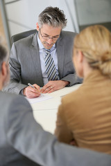 Mature couple signing contract in lawyer's office