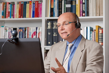 E-learning concept: lecturer at distance university with headset, computer and webcam talking, mooc...