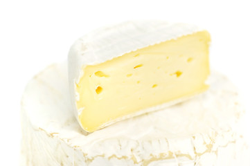 Round camembert cheese with a piece on white background