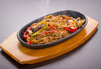 Soba noodles with meal and vegetables over black background