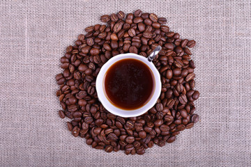 Cup of coffee with coffee beans on linen texture table