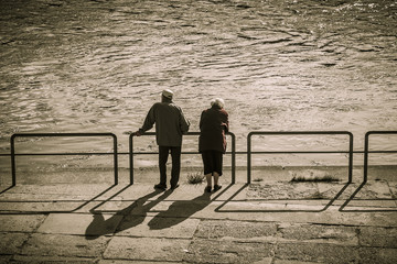 Silhouettes of two people near river, old age.