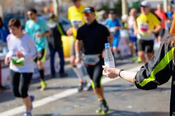 Marathon running race, runners on road, volunteer giving water