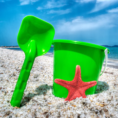 Fototapeta na wymiar green bucket and spade by the sea in hdr