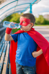 Superhero standing and drinking water from a bottle