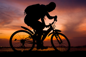 Fototapeta na wymiar Silhouette of backpacker ride mountain bike on bridge beside sea