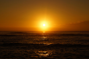 Sunrise over the ocean with waves rolling toward shore