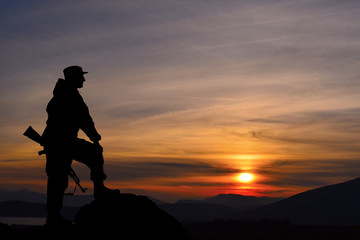Silhouette of military soldier officer with weapons at sunset