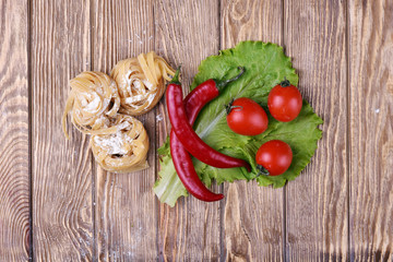 Pasta spaghetti noodles with chili pepper and tomatoes on table