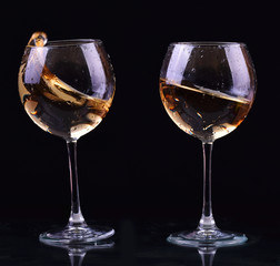 Set of glasses with white wine splash on dark background