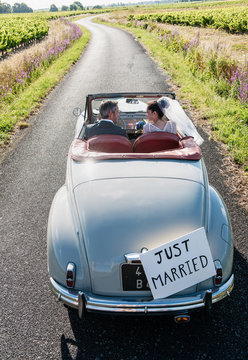 A newlywed couple is driving a retro car, top view