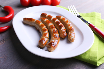 Grilled sausages on plate with vegetables on table close up