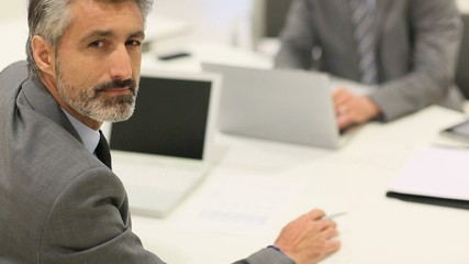 Portrait of mature businessman working on laptop