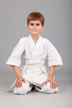 Karate boy in white kimono is sitting