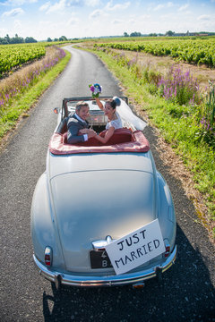 A newlywed couple is driving a retro car, top view