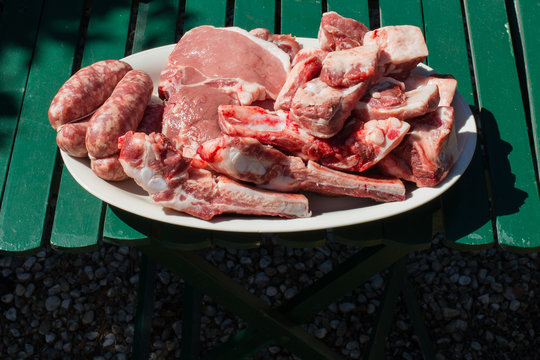 meat in a white ceramic tray on a green wooden  table