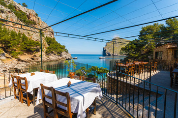 Restaurant tables in Sa Calobra bay, Majorca island, Spain - obrazy, fototapety, plakaty