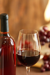 Bottle and glass of rose wine with grape on blurred background