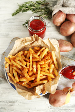 Tasty french fries on cutting board, on wooden table background