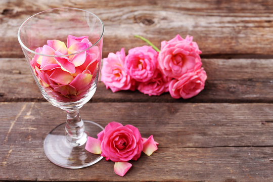 Beautiful pink rose in glass on wooden background