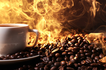 Pile of coffee beans and cup of hot coffee in beam