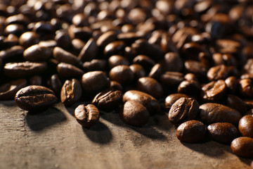 Fototapeta premium Pile of coffee beans on wooden table, closeup