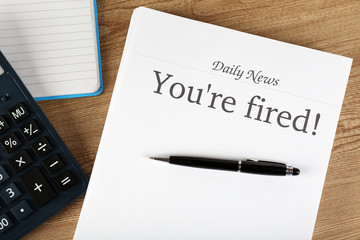 Message You're Fired on wooden table, top view