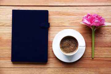 Cup of coffee with notebook and fresh flower